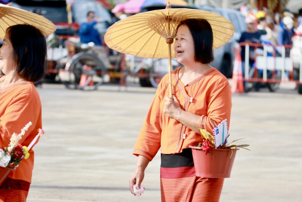 ผู้ร่วมขบวนถือเครื่องสักการะแบบล้านนาในงานปี 2568