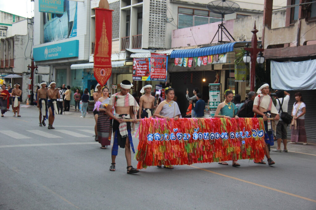 ผู้ร่วมขบวนแต่งกายพื้นเมืองนำป้ายประเพณีสลากย้อม ปี 2562