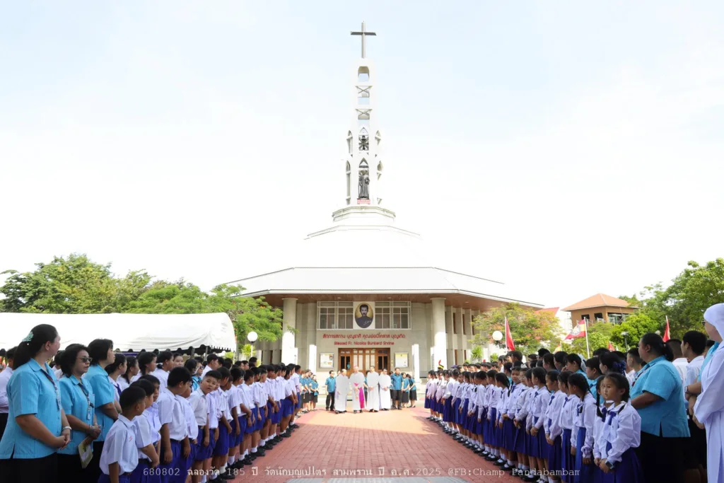 คณะสงฆ์เคลื่อนขบวนผ่านแถวนักเรียนและสมาชิกชุมชนในวันฉลอง ปี 2568