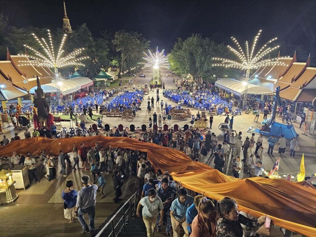 ภาพมุมสูงของประชาชนร่วมถือผ้าขึ้นสู่ฐานหลวงปู่ทวดองค์ใหญ่ในพิธีกลางคืนปี 2567