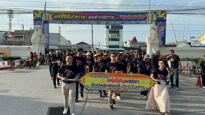 ประชาชนถือป้ายงานประเพณีแห่เทียนพรรษาจังหวัดสุพรรณบุรีร่วมเดินขบวนปี 2568