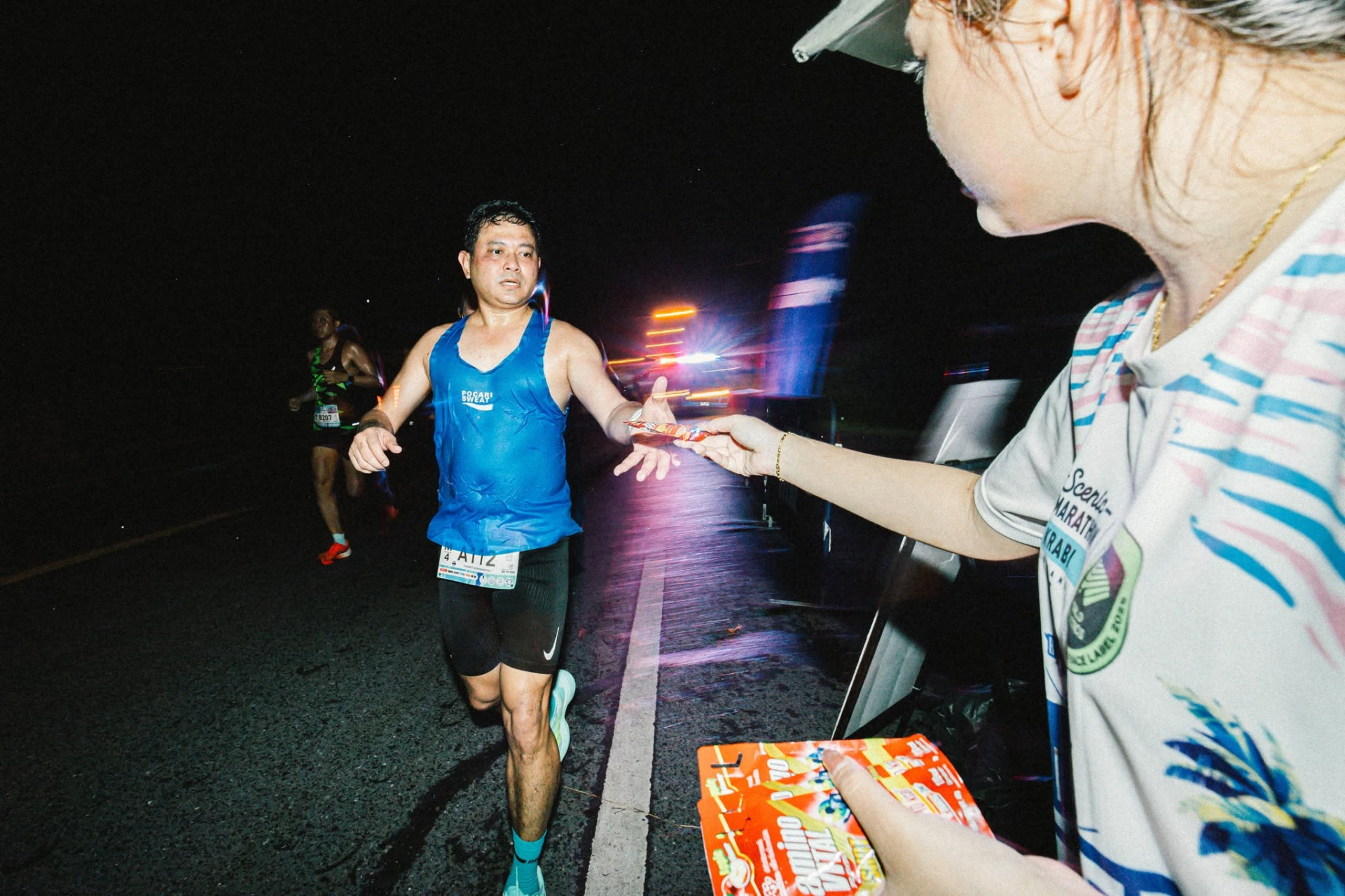 นักวิ่งรับของว่างจากอาสาสมัครบนเส้นทาง Scenic 1/2 Marathon Krabi ปี 2568