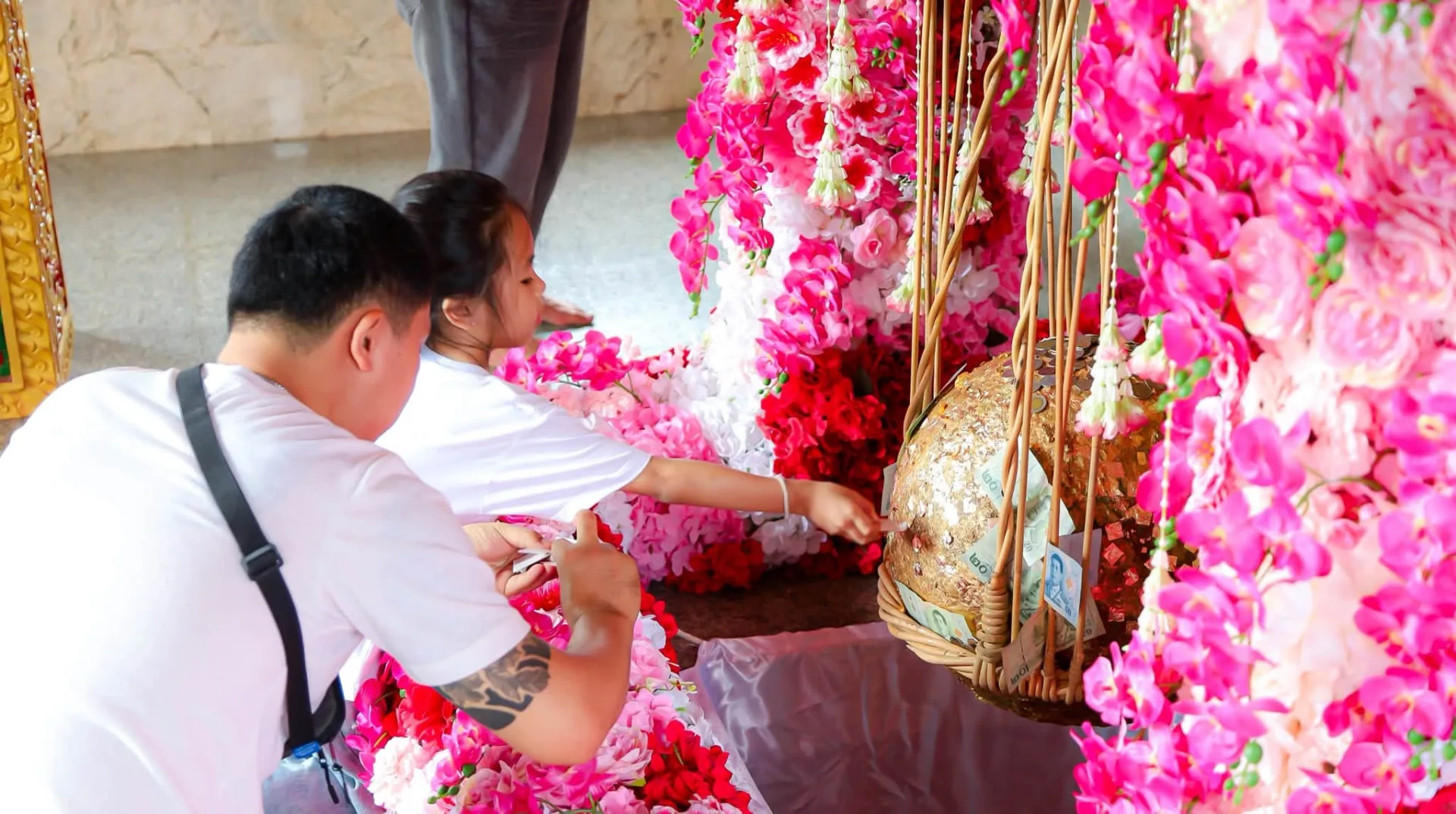 ผู้ใหญ่และเด็กร่วมปิดทองลูกนิมิตที่วัดพระธาตุดอยคำ
