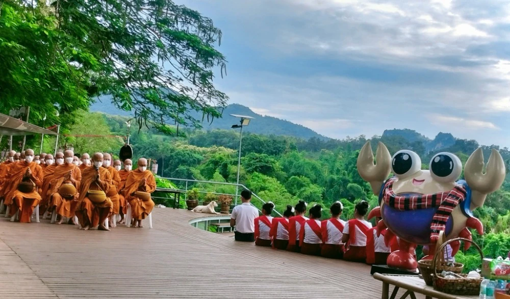 พระสงฆ์เดินรับบิณฑบาตผ่านจุดจัดวางอาหารริมแม่น้ำแควน้อย