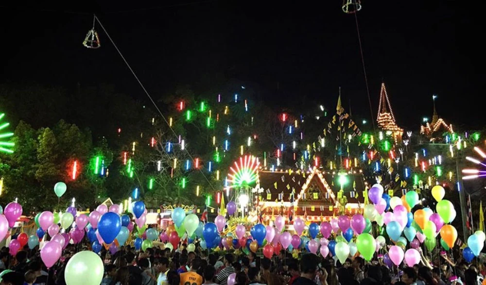 ผู้ร่วมงานถือกระทงสวรรค์และลูกโป่งในประเพณีลอยกระทงสวรรค์ 12 นักษัตร