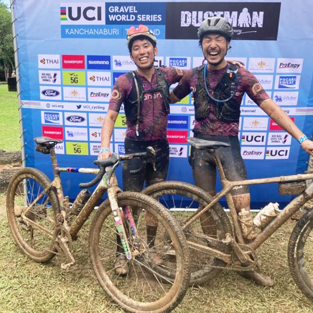 นักปั่นสองคนพร้อมจักรยานที่หน้าแบ็กดรอป Dustman UCI Gravel World Series ปี 2568
