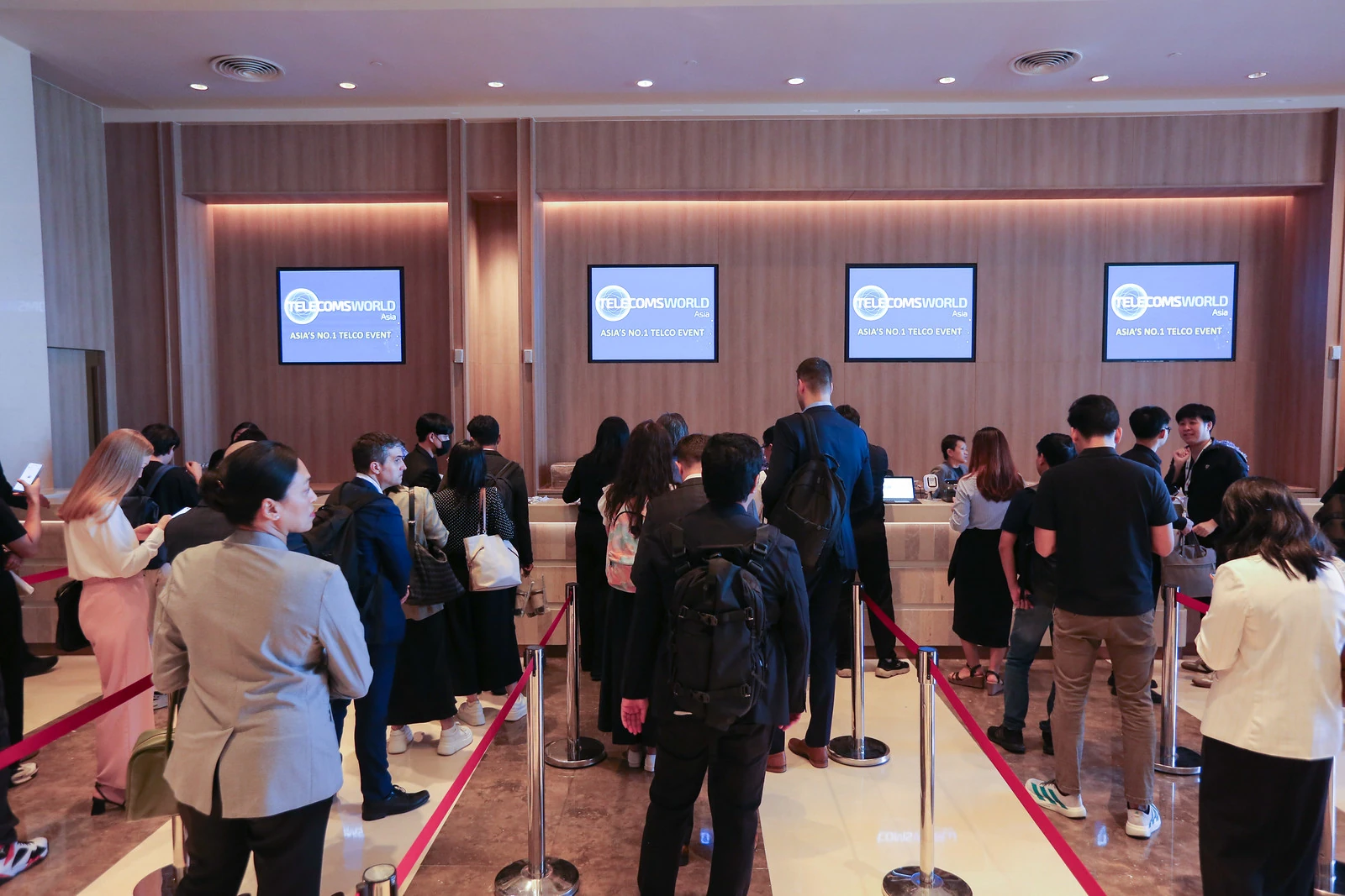 ผู้เข้าร่วมลงทะเบียนและพูดคุยบริเวณทางเข้างาน Telecoms World Asia 2025