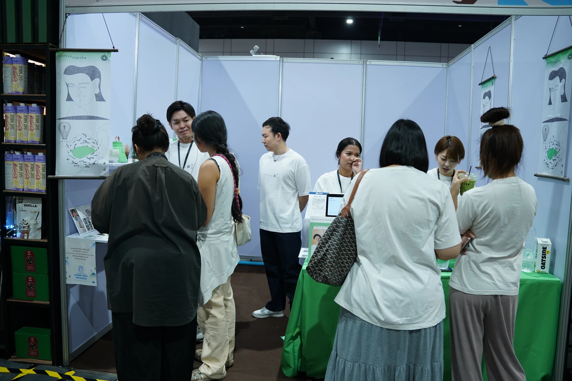 ผู้เข้าชมและทีมงานพูดคุยที่บูธ Zenkyu Matcha ใน Thailand Coffee Fest Year End 2025
