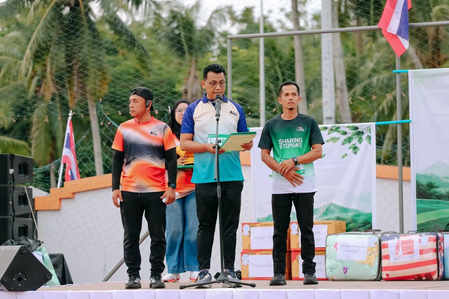 ผู้ร่วมกิจกรรมบนเวทีพร้อมไมโครโฟนและเสื้อ Sharing Steps ปีที่ 2 จากโพสต์ภาพงานของ RF Studio auctions