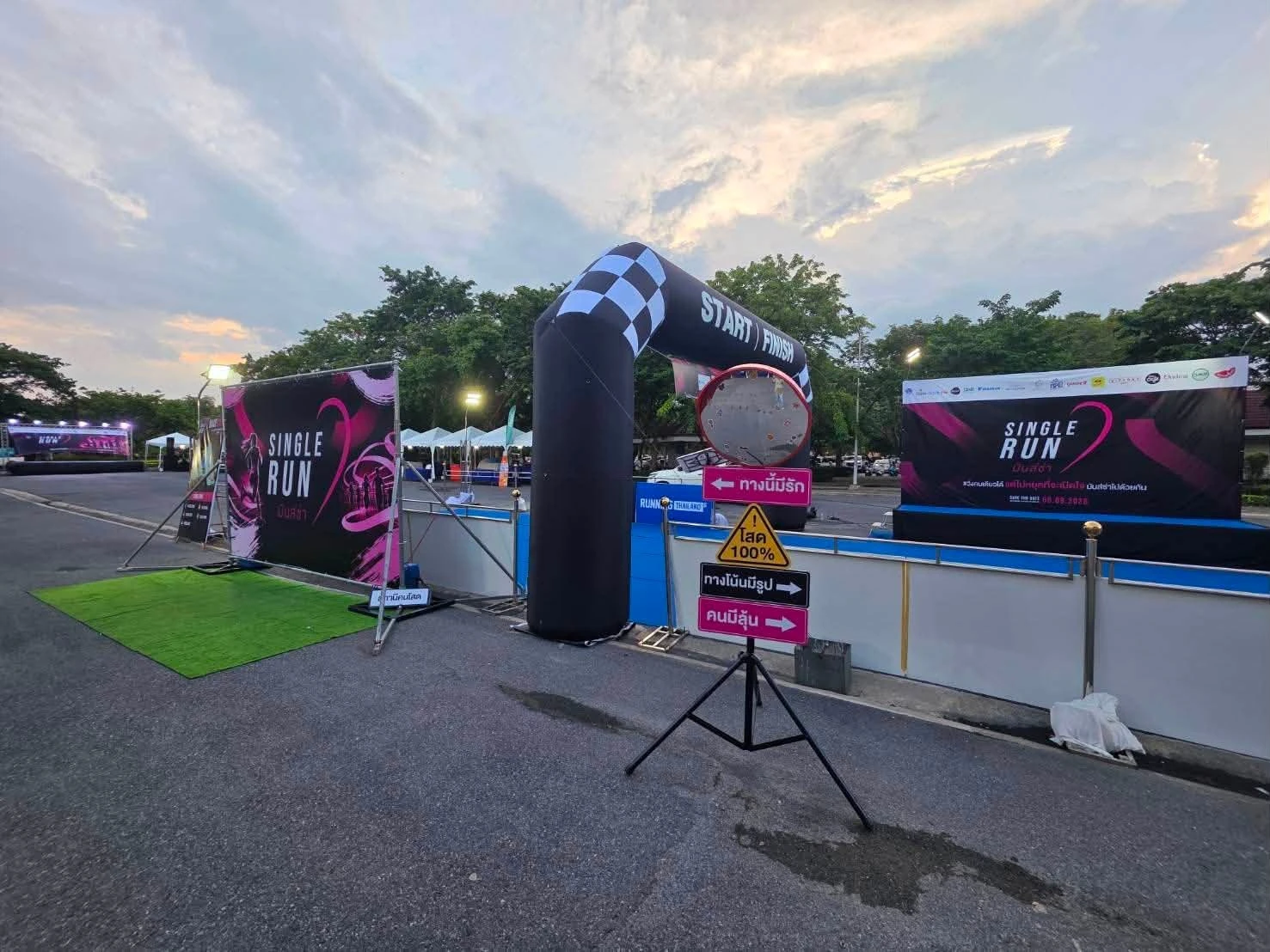 มุมด้านข้างซุ้ม Single Run พร้อมฉากถ่ายภาพพื้นสีเขียวและป้ายในพื้นที่เตรียมงาน จากภาพลำดับสองของโพสต์เดียวกัน