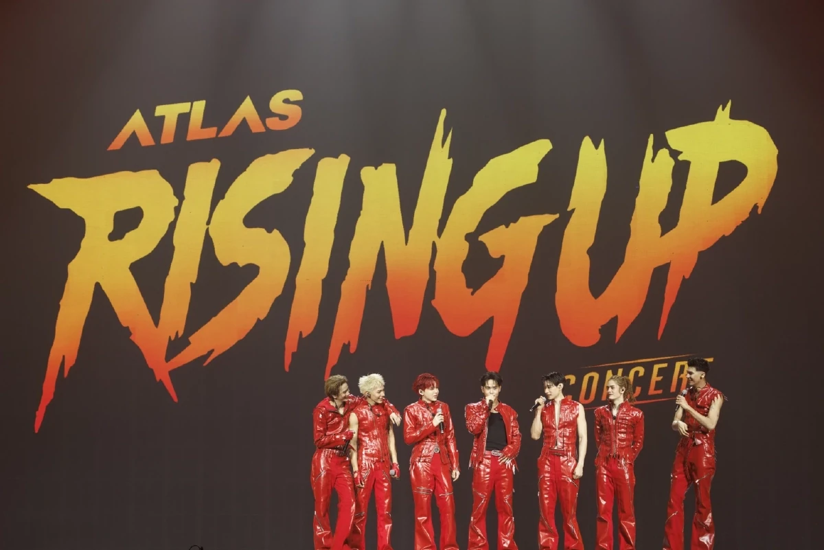 ศิลปินชุดแดงบนเวทีที่มีฉากชื่อ ATLAS RISING UP CONCERT จากรายงานหลังงานปี 2569