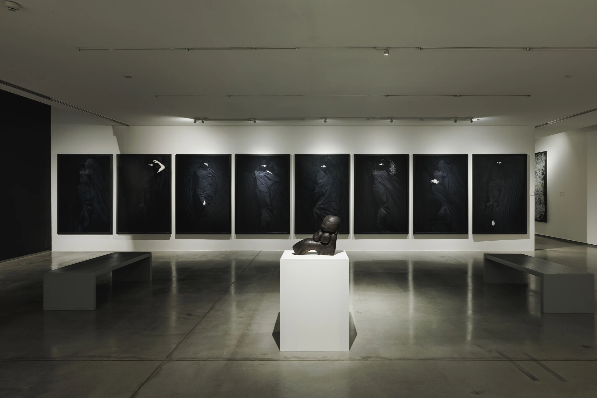 ภาพผลงานเรียงบนผนังและประติมากรรมบนแท่นกลางห้อง BLACK