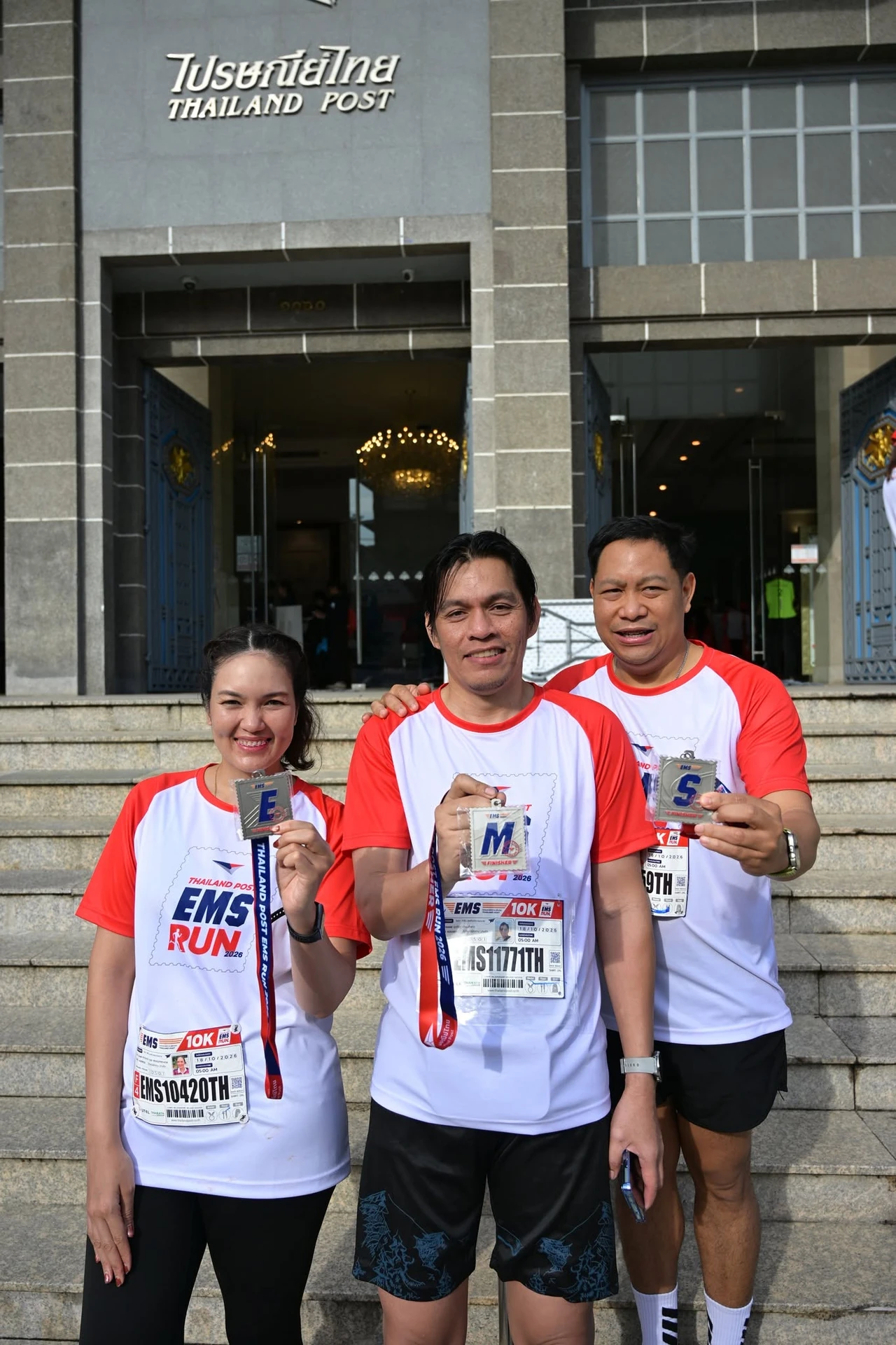 ผู้ร่วมงานถือเหรียญ E–M–S บริเวณอาคารไปรษณีย์ จากชุดภาพของเพจ Thailand Post EMS RUN 2026