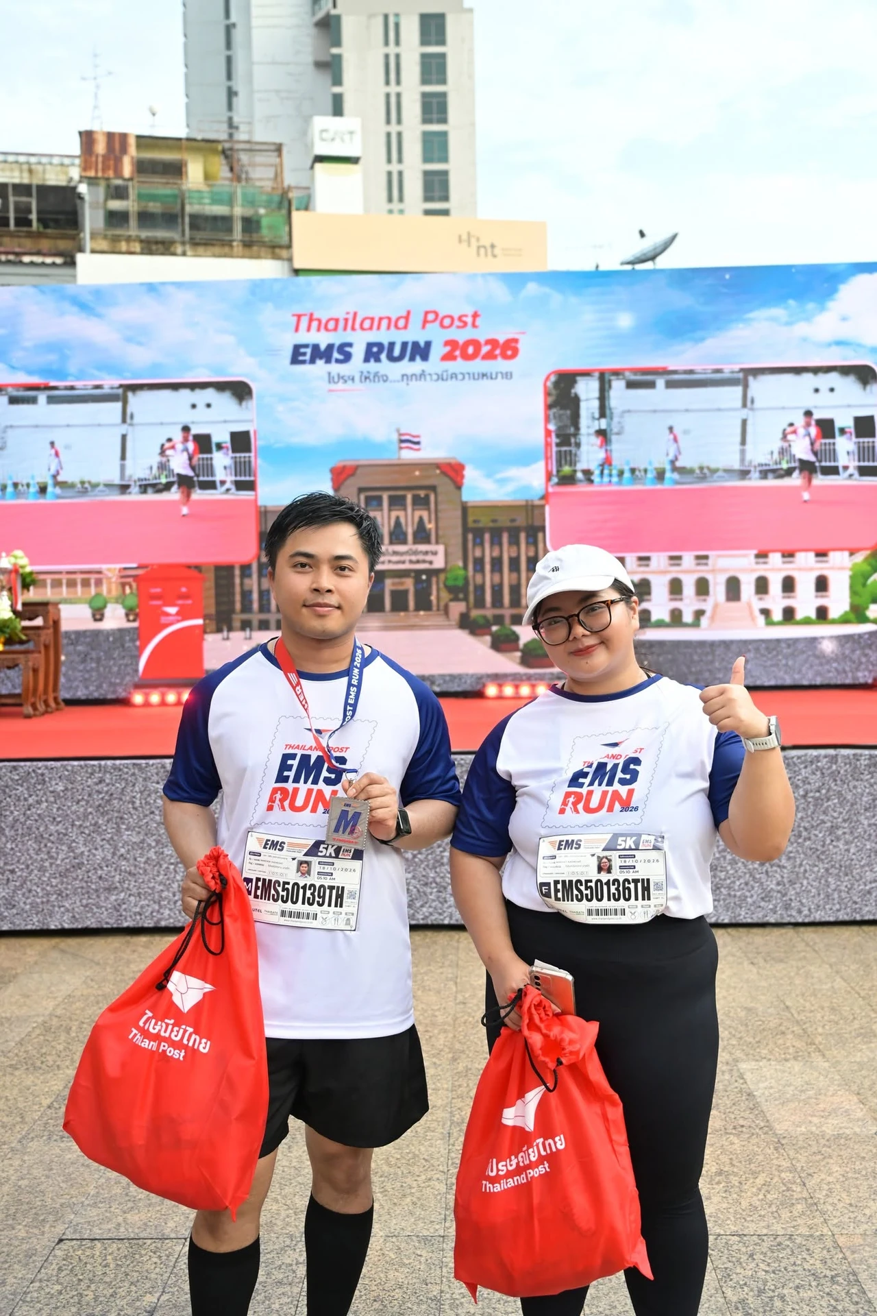 ผู้ร่วมงานบริเวณเวทีที่มีป้าย Thailand Post EMS RUN 2026 จากชุดภาพของเพจงาน