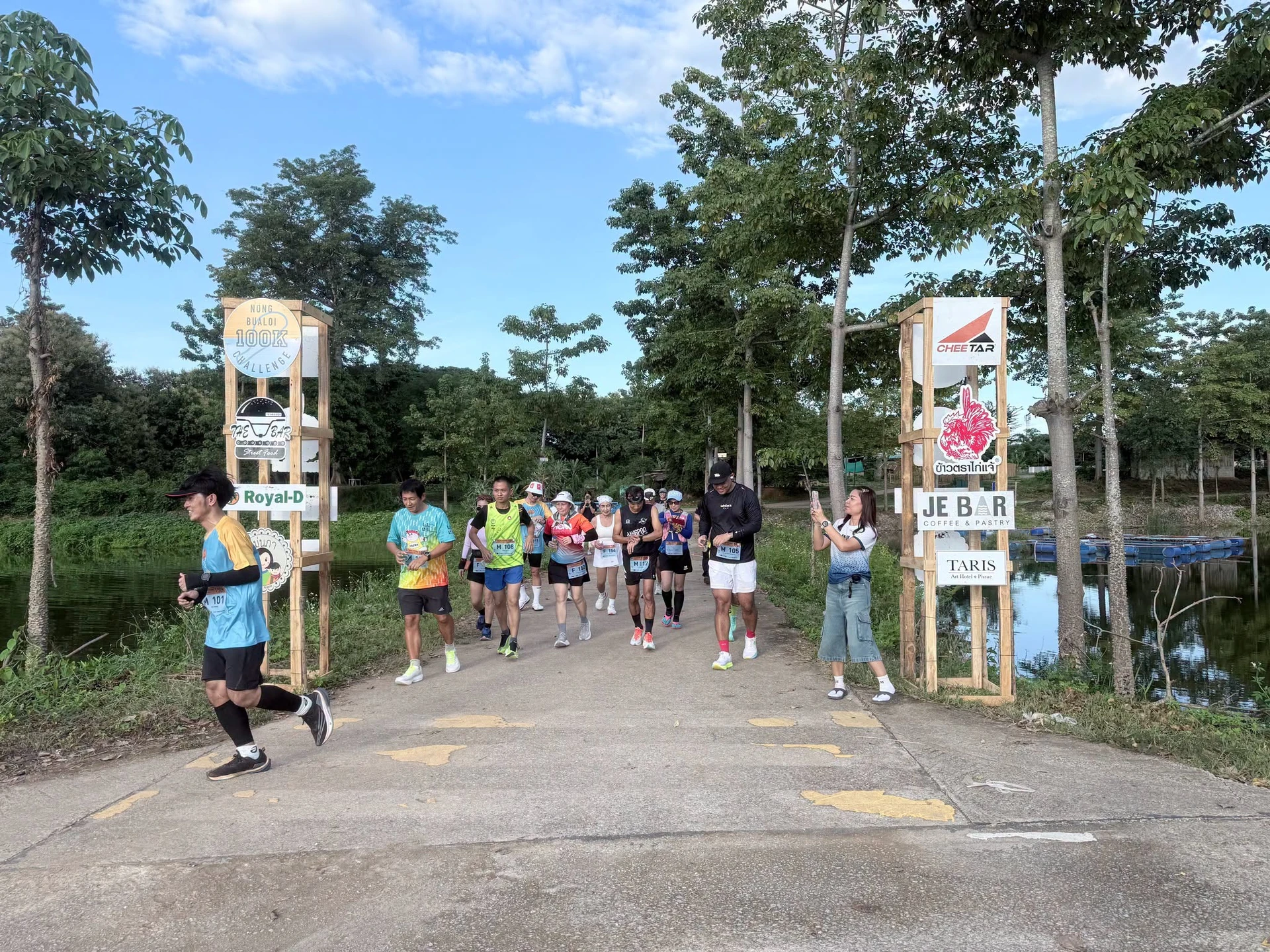 นักวิ่งบริเวณป้าย Nong Bualoi 100K Challenge ริมหนองบัวลอยในภาพแรกจากรายงานผู้จัด