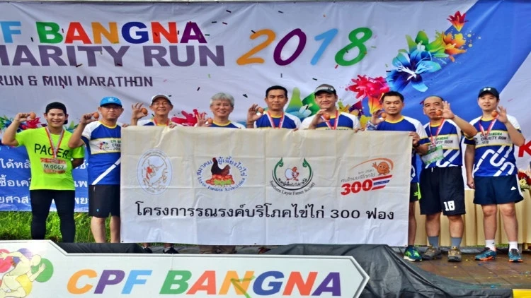 ผู้ร่วมกิจกรรมยืนด้านหน้าป้าย CPF Bangna Charity Run 2018 ในรายงานกรุงเทพธุรกิจ