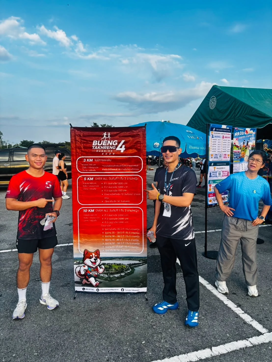 ภาพผู้คนยืนข้างป้ายประชาสัมพันธ์บึงตะเครง Running 4 จากเพจผู้จัด วิ่งสานฝัน ปันโดมให้น้อง — ต้นทางไม่ระบุปีถ่าย ไม่ใช่ภาพการแข่งขันวันที่ 27 ธันวาคม 2569