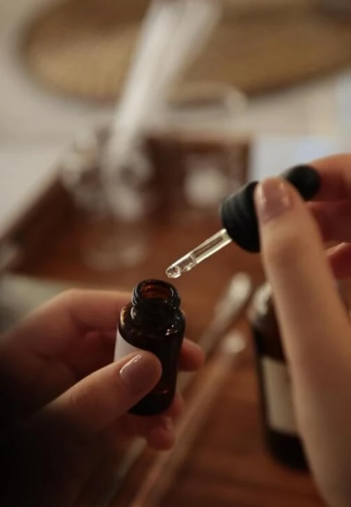 ภาพตัวอย่างมือใช้หลอดหยดบริเวณขวดจากหน้าหลักสูตร Craft Your Signature Scent ของ Blend & Amber บน ClassBento