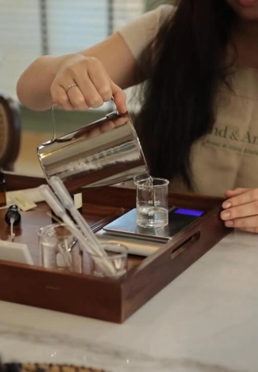 ภาพตัวอย่างการเทลงภาชนะบริเวณโต๊ะจากหน้าหลักสูตร Craft Your Signature Scent เดียวกัน ไม่ระบุรอบกิจกรรม