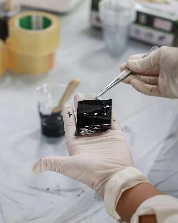 ภาพตัวอย่างมือสวมถุงมือใช้คีมบริเวณโต๊ะจากประกาศห้องเรียนจำลองนิติวิทยาศาสตร์ชุดเดียวกัน