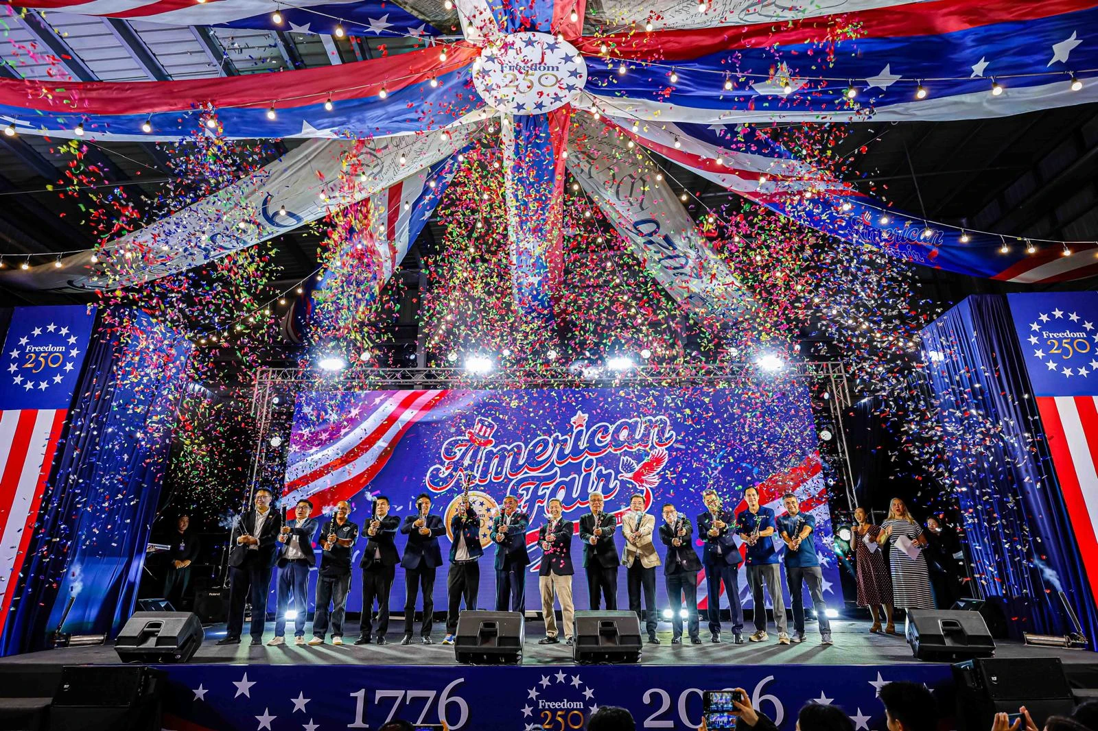 ภาพเปิดงาน American Fair หาดใหญ่ บนเวทีพร้อมป้าย American Fair และ Freedom 250 จากอัลบั้มสถานทูต