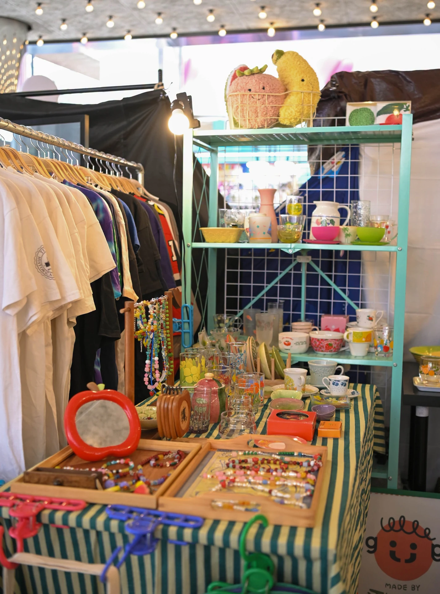 ภาพมุมร้านจัดแสดงของใช้ ของสะสม และเสื้อผ้าจากอัลบั้มเทหลบฝน SS9 ชุดเดียวกัน