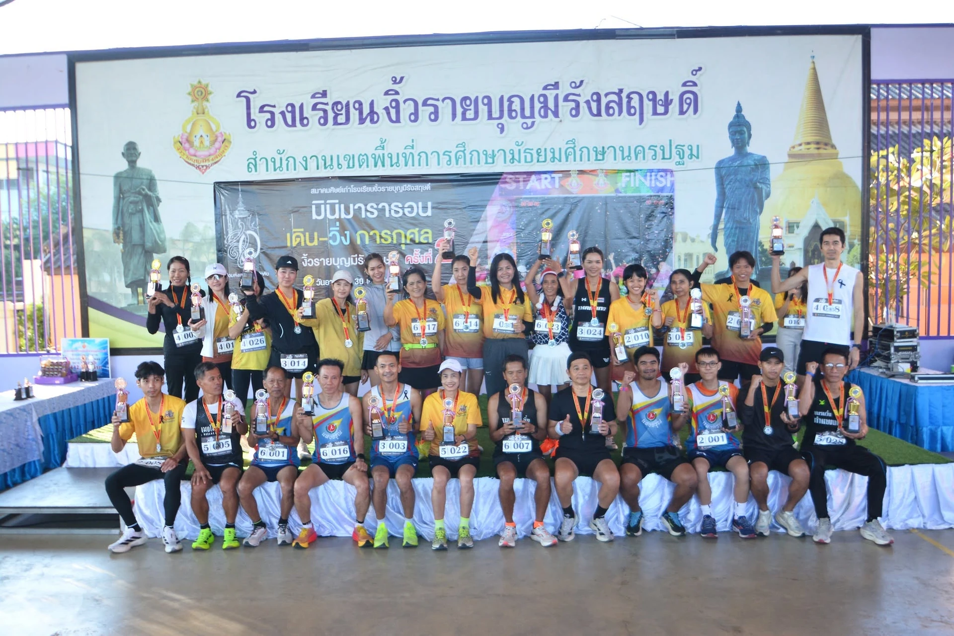 ภาพกลุ่มบริเวณเวทีจากรายงานงิ้วรายมินิมาราธอนครั้งที่ 2 คงภาพเต็มและป้ายโครงการปี 2568