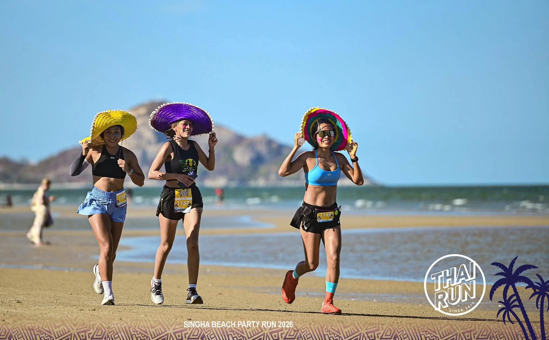 ผู้ร่วมกิจกรรมวิ่งบนชายหาดสวมหมวกสีสันในภาพครั้งก่อน พร้อมกรอบ SINGHA BEACH PARTY RUN 2026 และตรา THAI RUN จากต้นทาง คงภาพเต็ม