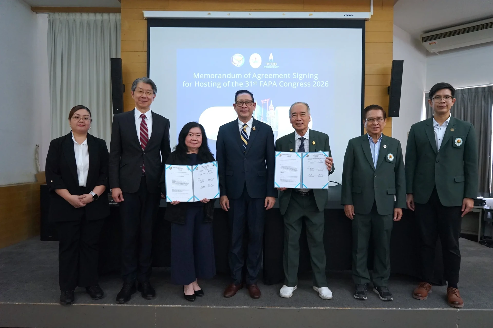 ภาพหมู่พร้อมแฟ้มเอกสารเปิดหน้าฉากพิธีลงนามเพื่อเตรียมจัดประชุม FAPA 2026 จากรายงานวันที่ 7 กุมภาพันธ์ 2568 คงภาพเต็ม