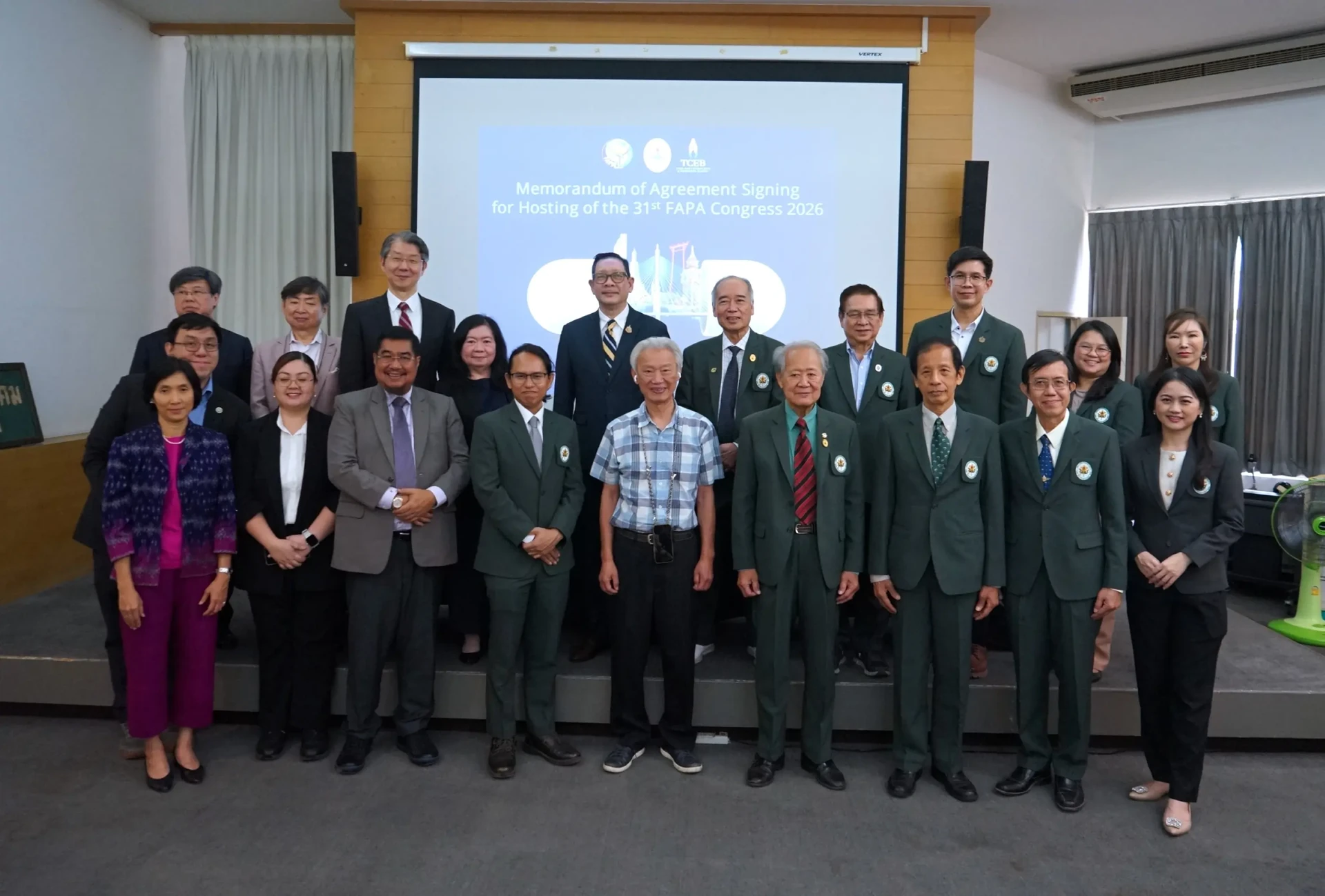 ภาพหมู่ขนาดใหญ่หน้าจอพิธีลงนามเพื่อเตรียมจัดประชุม FAPA 2026 จากรายงานกิจกรรมเดียวกันในปี 2568 คงภาพเต็ม
