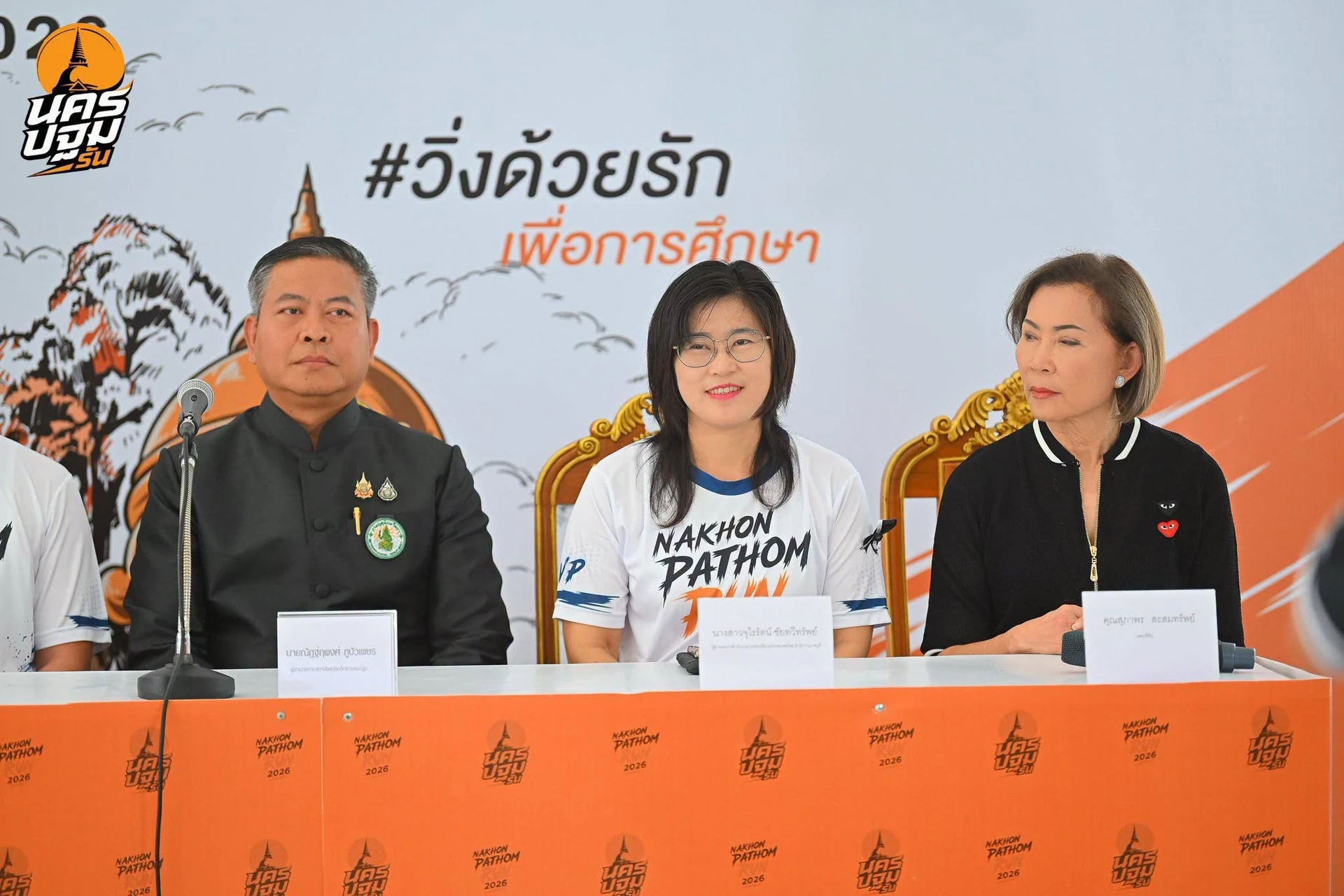 บรรยากาศบริเวณโต๊ะแถลงข่าวพร้อมไมโครโฟนและฉากนครปฐมรัน จากชุดรายงานวันที่ 3 กรกฎาคม 2569 คงภาพเต็ม ไม่ใช่ภาพวันแข่งขัน