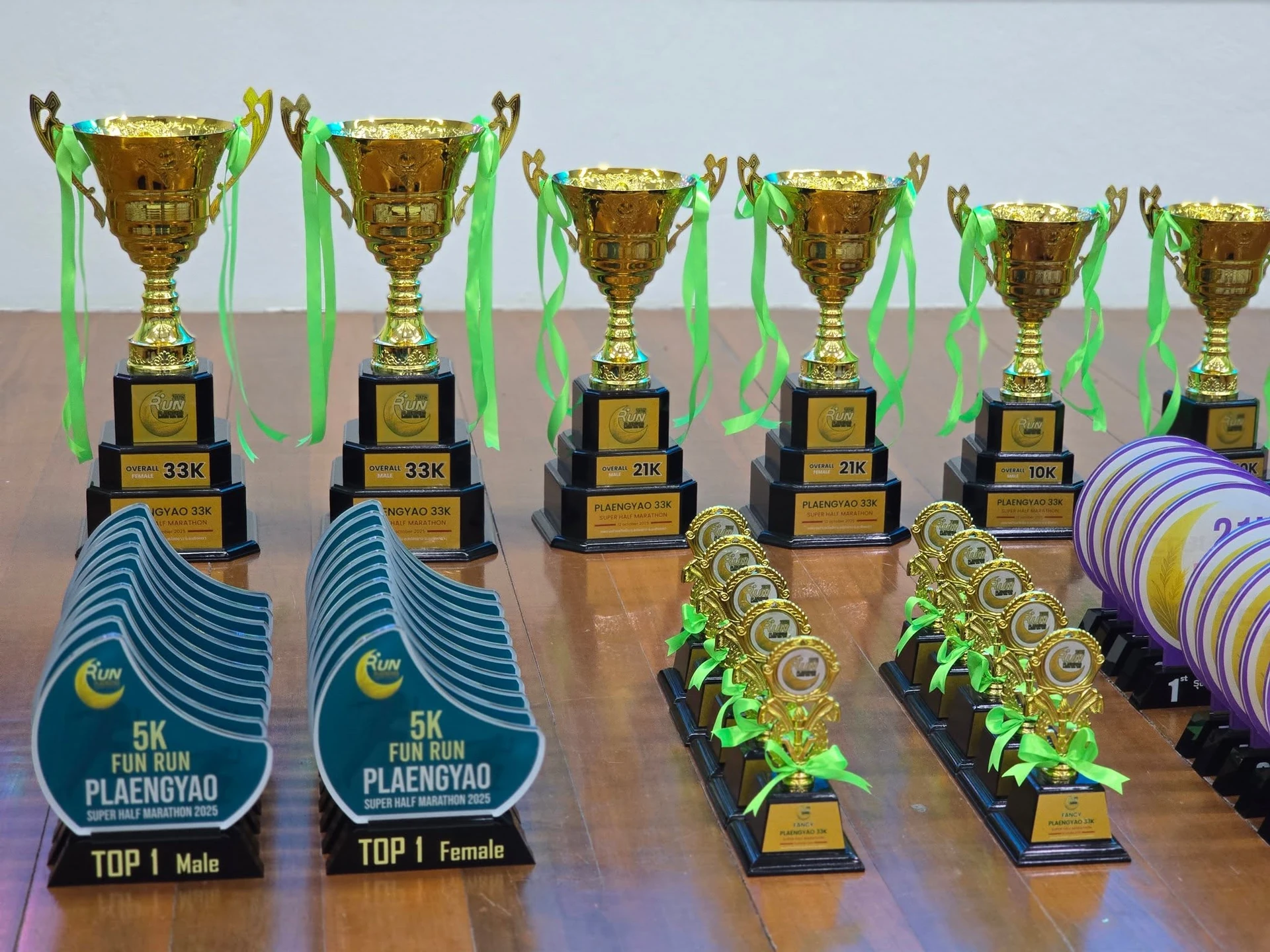 ถ้วยรางวัลเรียงบนโต๊ะจากชุดภาพเตรียมงาน PLAENGYAO ครั้งก่อน คงภาพเต็มและชื่อรุ่นเดิมบนถ้วย