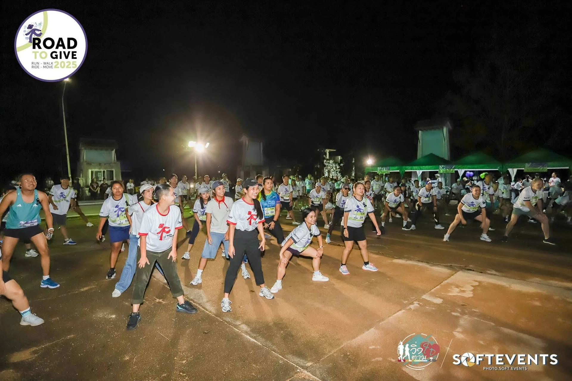 กลุ่มผู้ร่วมงานวอร์มอัพในลานช่วงแสงไฟ จากภาพย้อนหลัง Road To Give Phuket ที่เขื่อนบางวาด คงภาพเต็มพร้อมตรางานและเครดิตเดิม ไม่ใช่ภาพงานปี 2569