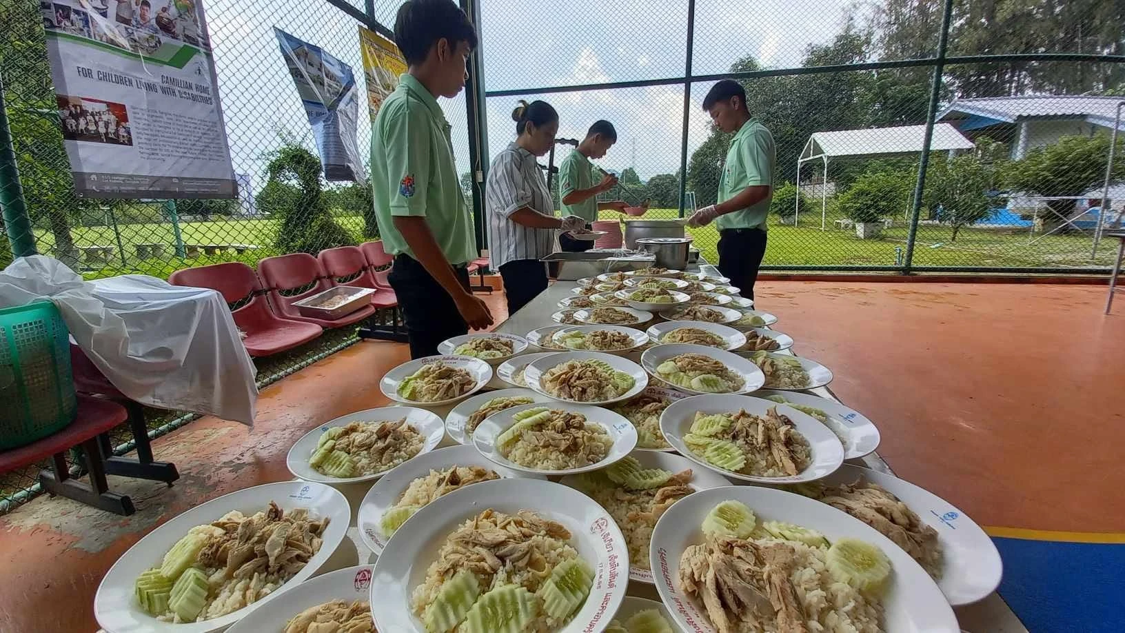 โต๊ะอาหารที่จัดเป็นจานเรียงกันและผู้คนบริเวณโต๊ะ จากรายงานช่วยเตรียมค่ายกางเขนแดงปี 2567