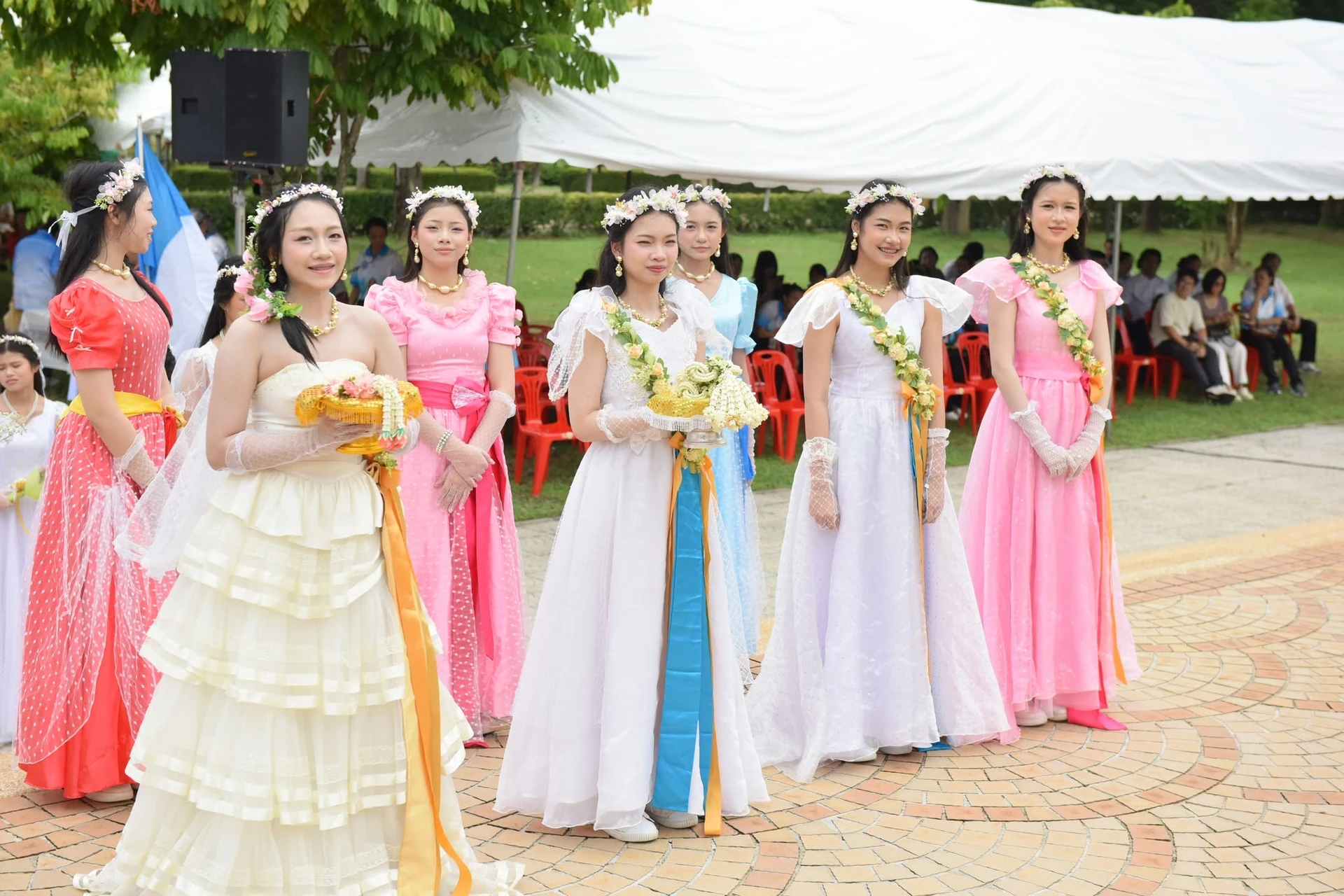 กลุ่มคนถือพานดอกไม้บนลานใกล้เต็นท์ จากรายงานฉลองวัดมารีสมภพ กบินทร์บุรี ปี 2569