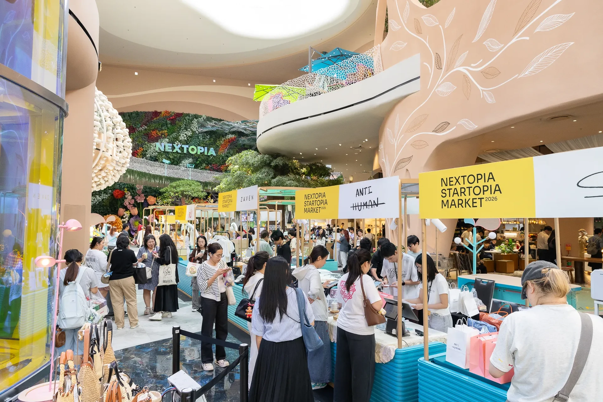 บูธและผู้คนบริเวณทางเดินใต้ป้าย NEXTOPIA STARTOPIA MARKET 2026 จากข่าวประชาสัมพันธ์สยามรัฐ