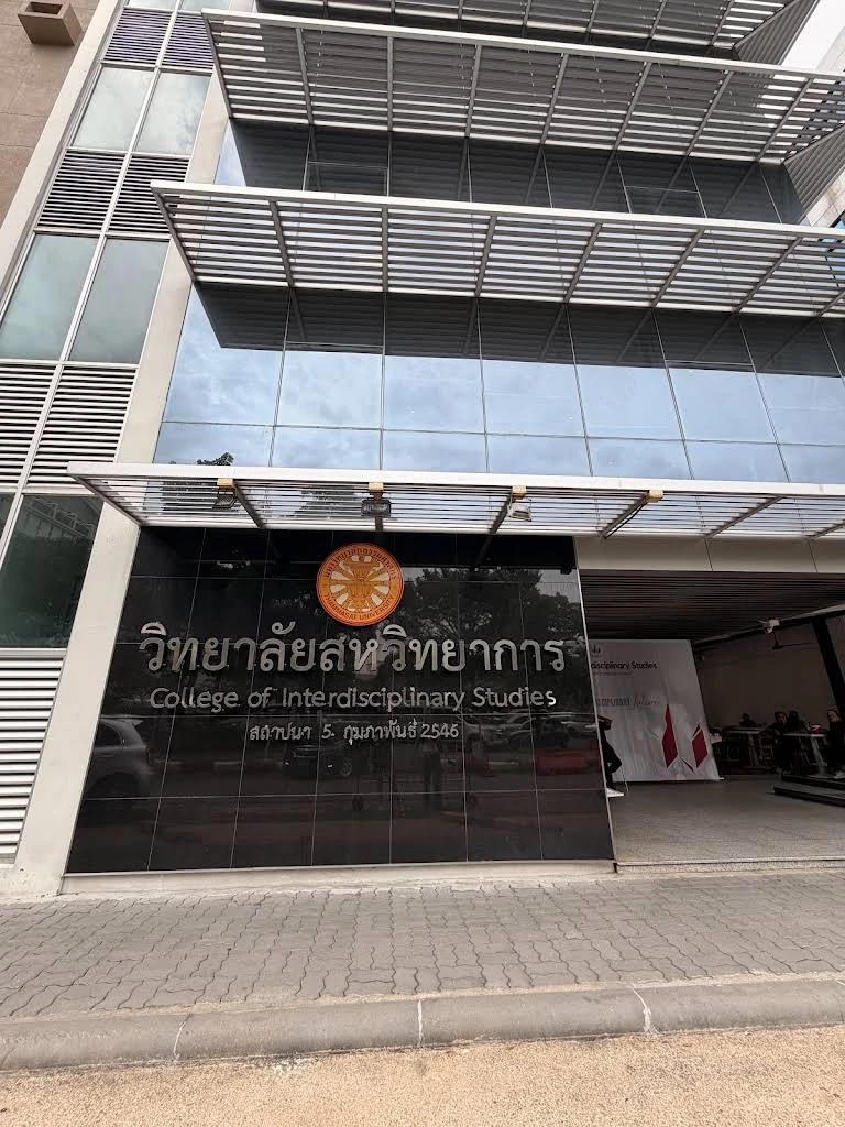 ภาพภายนอกอาคารวิทยาลัยสหวิทยาการ มหาวิทยาลัยธรรมศาสตร์ ท่าพระจันทร์ ข้อมูลเวลาถ่ายบน Google Maps ระบุเดือนกรกฎาคม 2569 — ภาพสถานที่ย้อนหลัง ไม่ใช่ภาพภายใน Common Room ชั้น 2 ภาพกิจกรรม VERSE OF BEGINNINGS วันที่ 9 กันยายน 2569 หรือการเตรียมงาน และไม่ใช้ยืนยันผังงานหรือสภาพพื้นที่ปัจจุบัน
