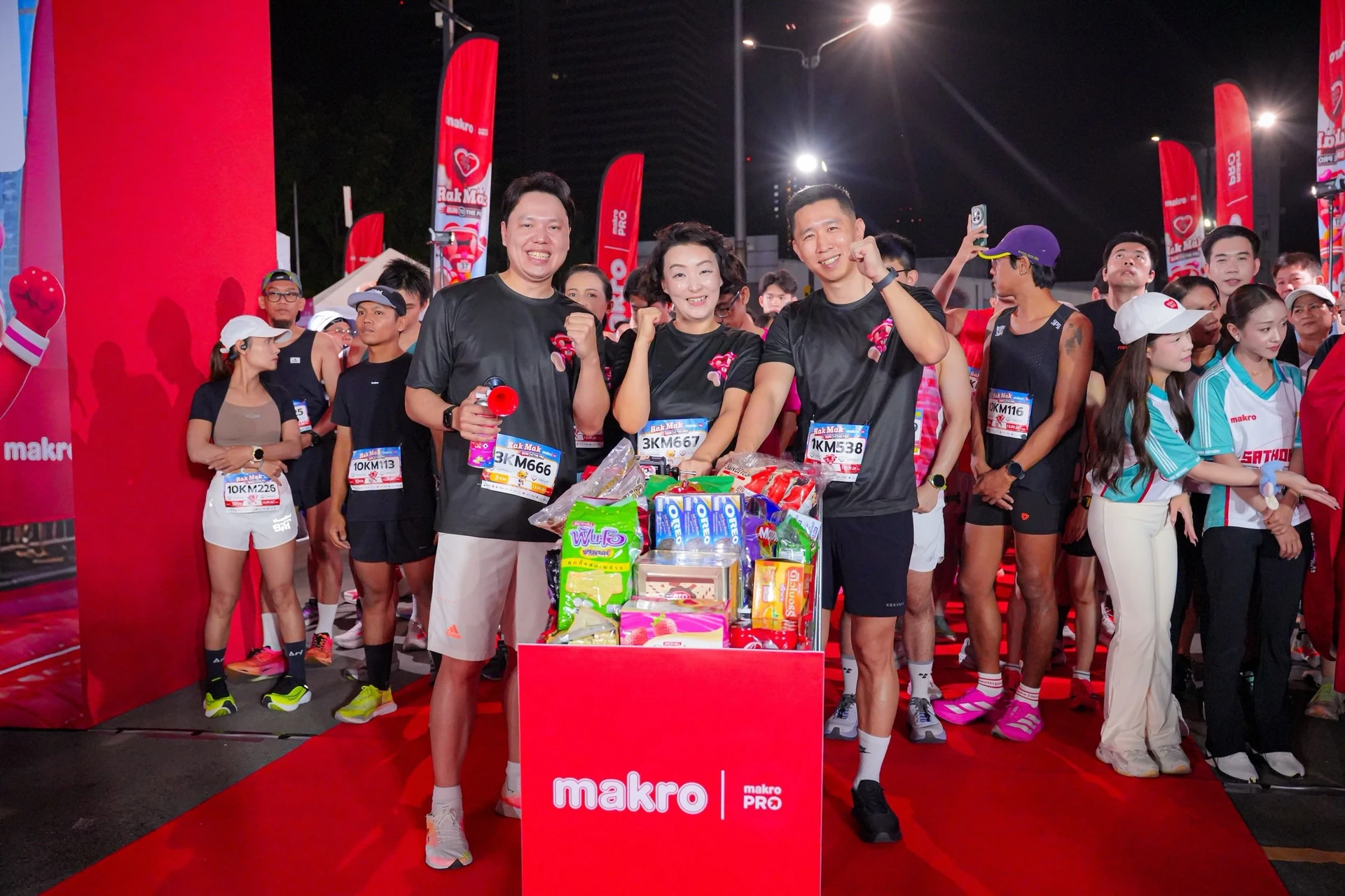 กลุ่มคนและแท่นจัดวางสินค้าในบริเวณ Rak Mak Run จากภาพเก็บตกแม็คโคร