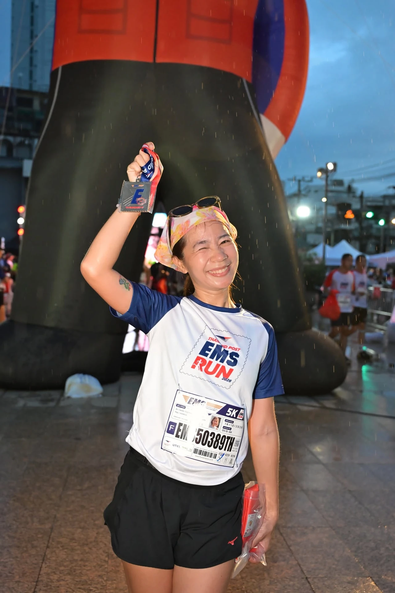 การถือเหรียญบริเวณสิ่งตกแต่งขนาดใหญ่ของ Thailand Post EMS RUN ปี 2569