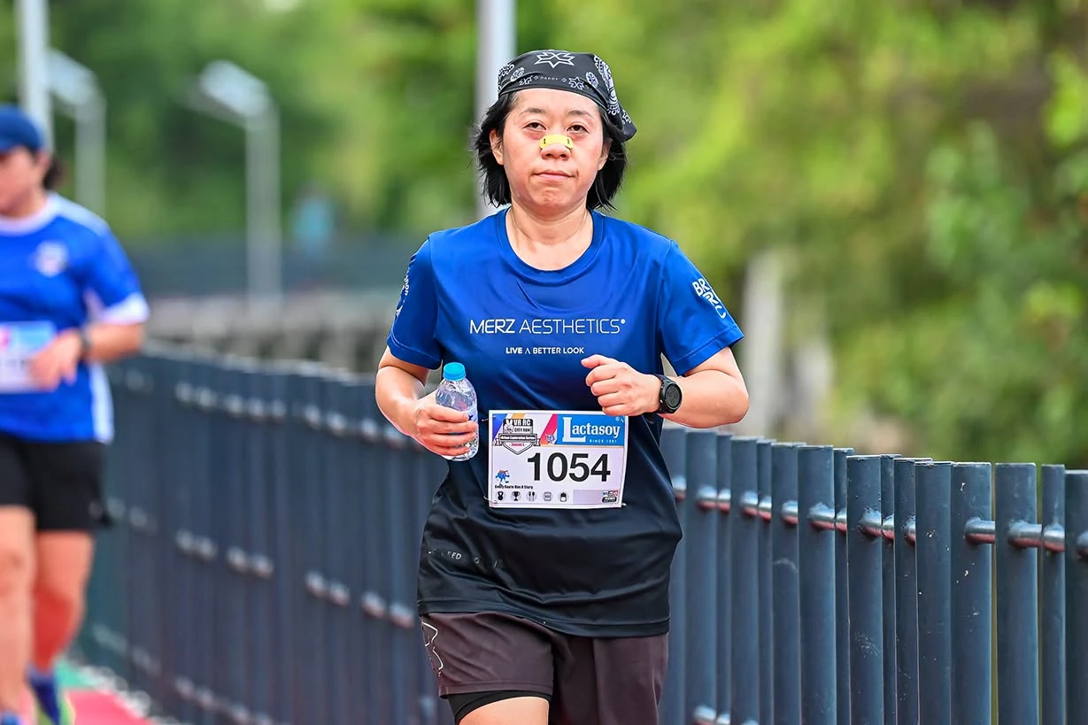 นักวิ่งสวมหมายเลข 1054 กำลังวิ่งข้างราวสีน้ำเงินใน City Run Season 5 EP.1 คลองสวน ไม่ระบุวันถ่าย