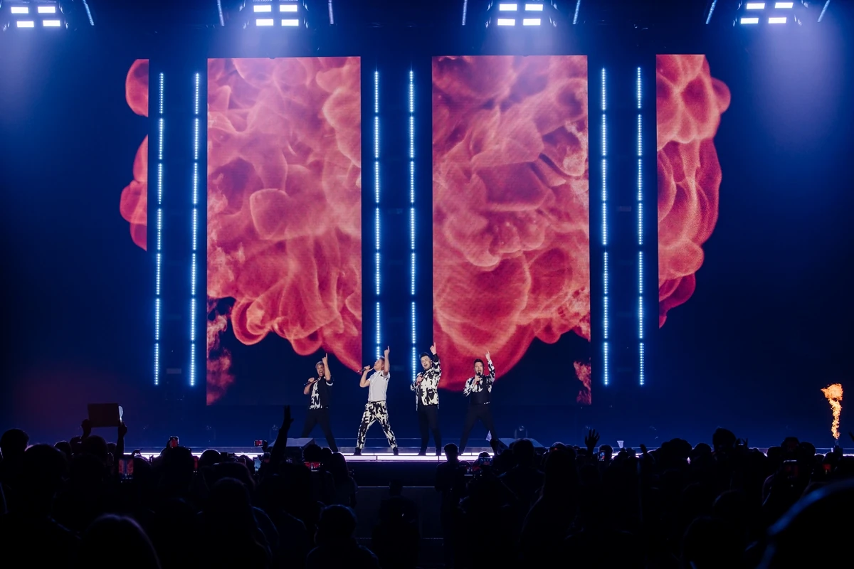สมาชิก Westlife ร้องเพลงบนเวทีพร้อมจอแสงสีและผู้ชมในคอนเสิร์ต The Wild Dreams Tour กรุงเทพฯ ปี 2566