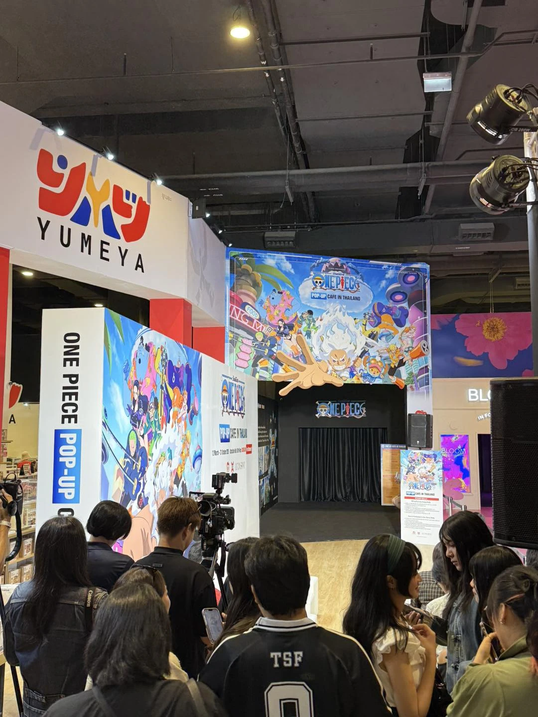 ผู้ร่วมงานอยู่หน้าเวทีที่มีป้าย ONE PIECE Pop-up Cafe in Thailand ที่ไอคอนสยาม ปี 2569