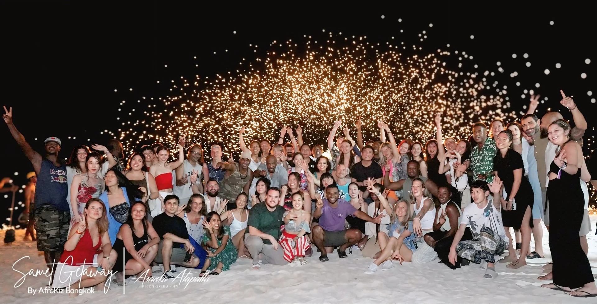 ภาพกลุ่มผู้ร่วมค่าย Samet Getaway ของ AfroKiz บนชายหาดพร้อมประกายไฟ จากอัลบั้มปี 2568 ไม่ใช่หัวหิน