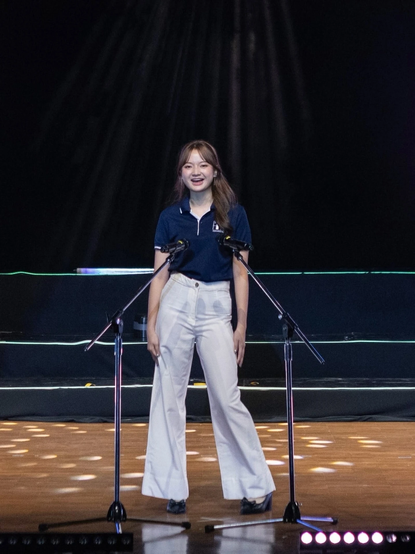 ผู้ร่วมกิจกรรมยืนระหว่างไมโครโฟนบนเวที จากโพสต์ประกาศสมาชิก TUTV รุ่นที่ 14 ไม่ระบุวันถ่าย