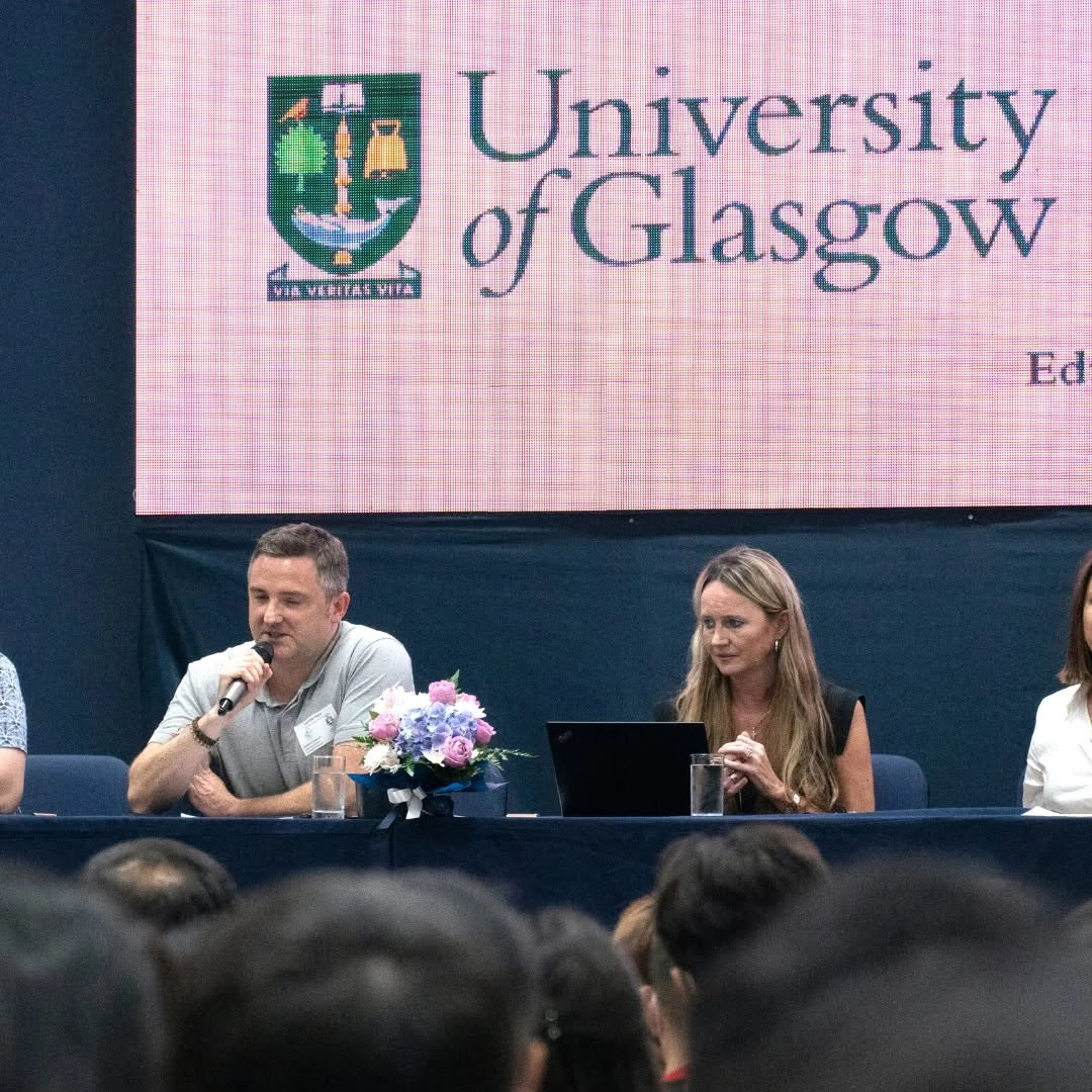 วิทยากรถือไมโครโฟนบนเวที UK Universities Panel ครั้งก่อน จากโพสต์ Harrow ปี 2565 ไม่ใช่งานปี 2569