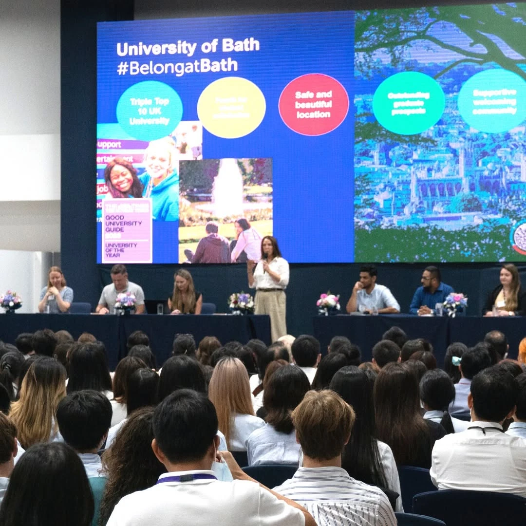วิทยากรยืนอธิบายบนเวทีและผู้ฟังใน UK Universities Panel ครั้งก่อน จากโพสต์ Harrow ปี 2565