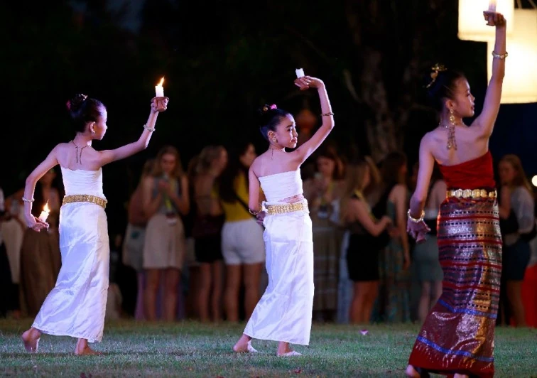 นักแสดงถือเทียนบนสนามหญ้าในภาพประกอบ Chiang Mai Heritage Sky Lanterns Festival ไม่ระบุวันถ่าย