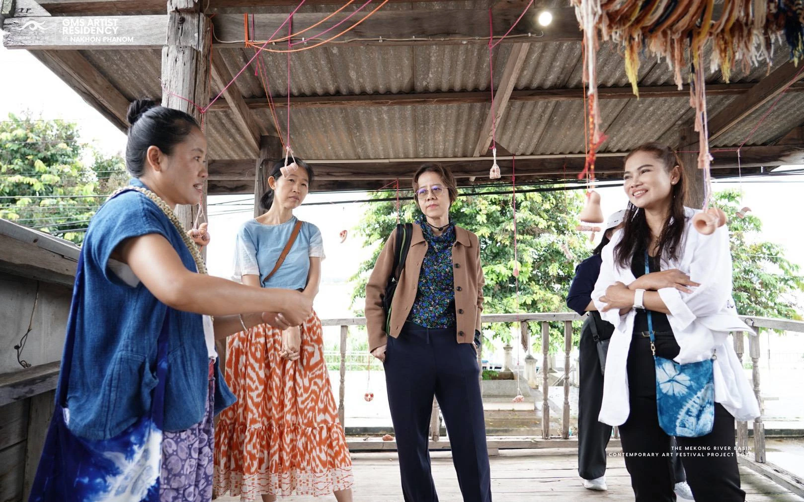 ผู้ร่วมชมงานพูดคุยบริเวณผลงานแขวนใต้หลังคา จากรายงานนิทรรศการโขงเอยบ่เคยลืม ธาตุพนม ปี 2569
