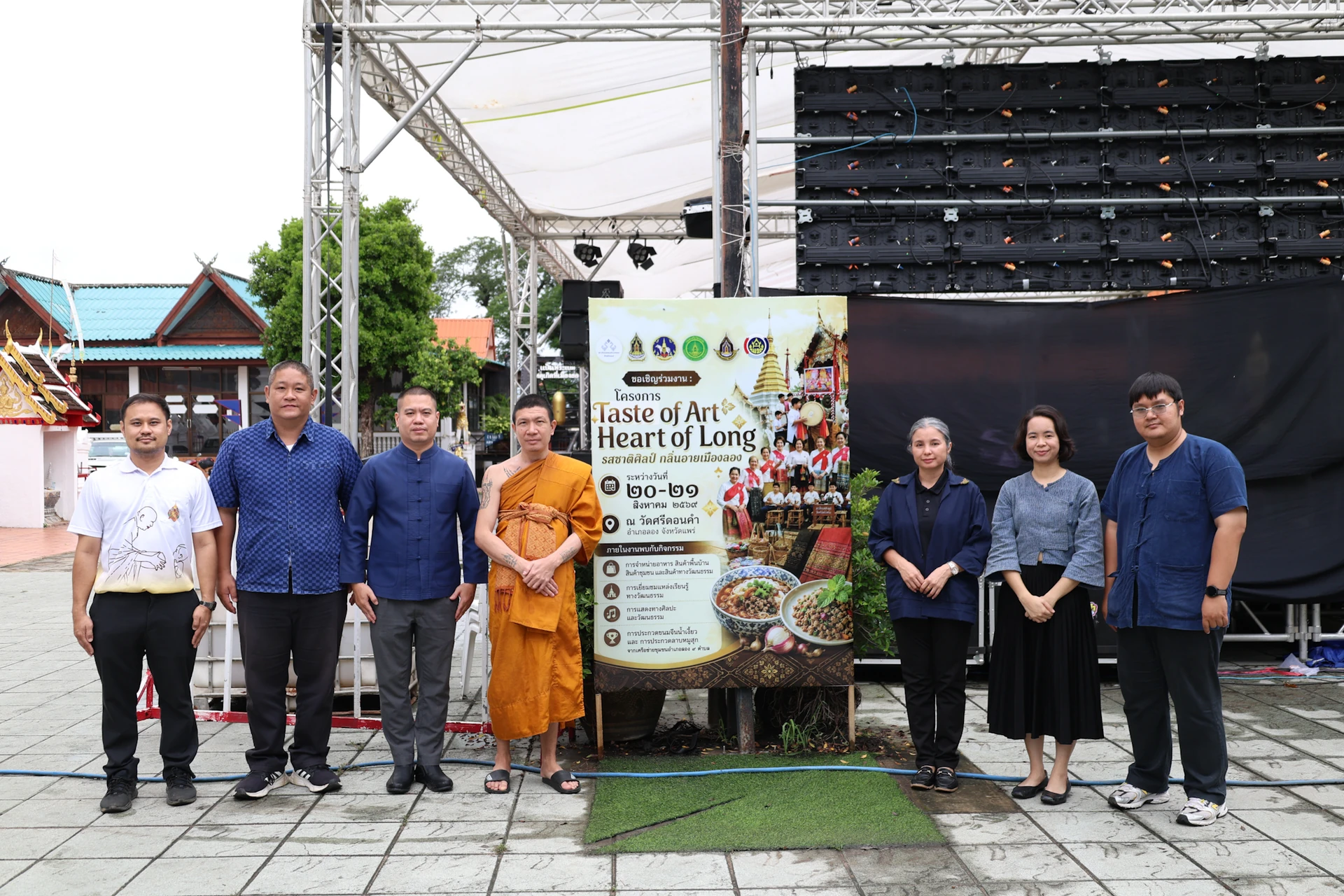 กลุ่มคนยืนข้างป้าย Taste of Art, Heart of Long ณ วัดศรีดอนคำ จากรายงานงานปี 2569