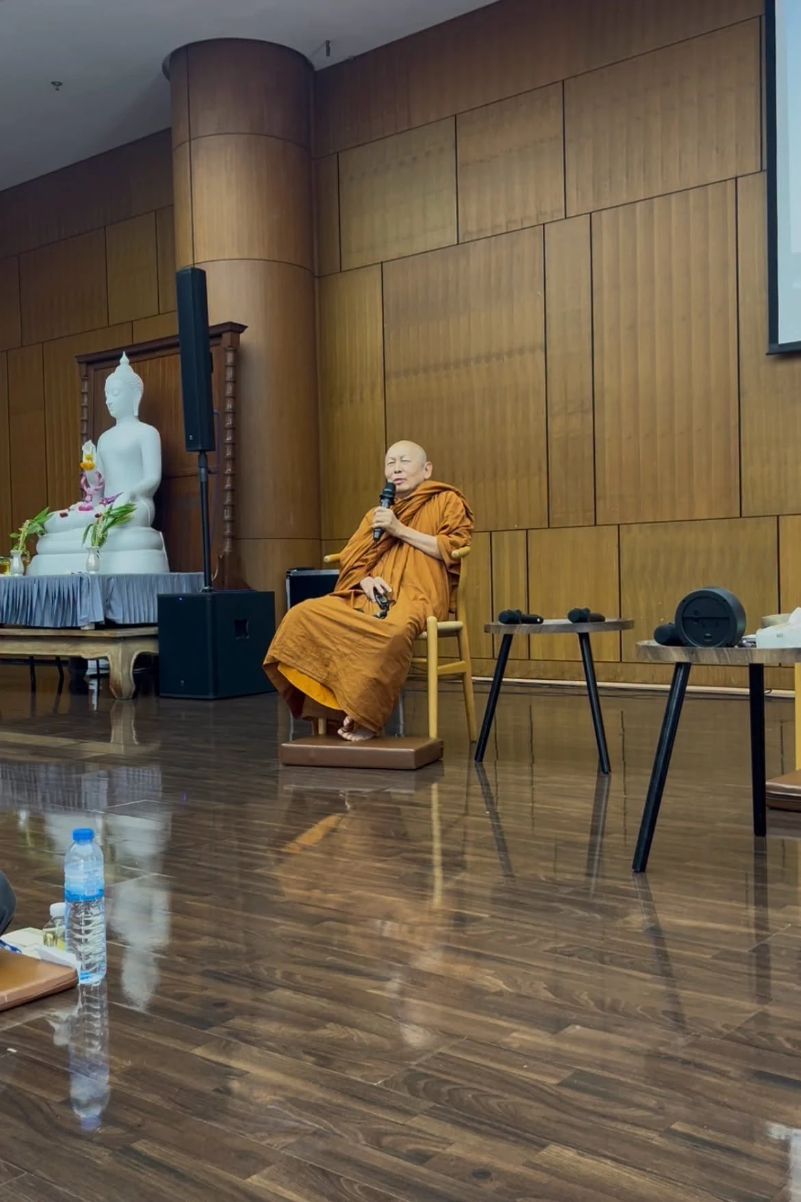 พระสงฆ์นั่งถือไมโครโฟนหน้าห้องในกิจกรรมเป็นมิตรกับความตาย วันที่ 16 สิงหาคม 2569 ไม่ระบุเวลาถ่ายรายภาพ